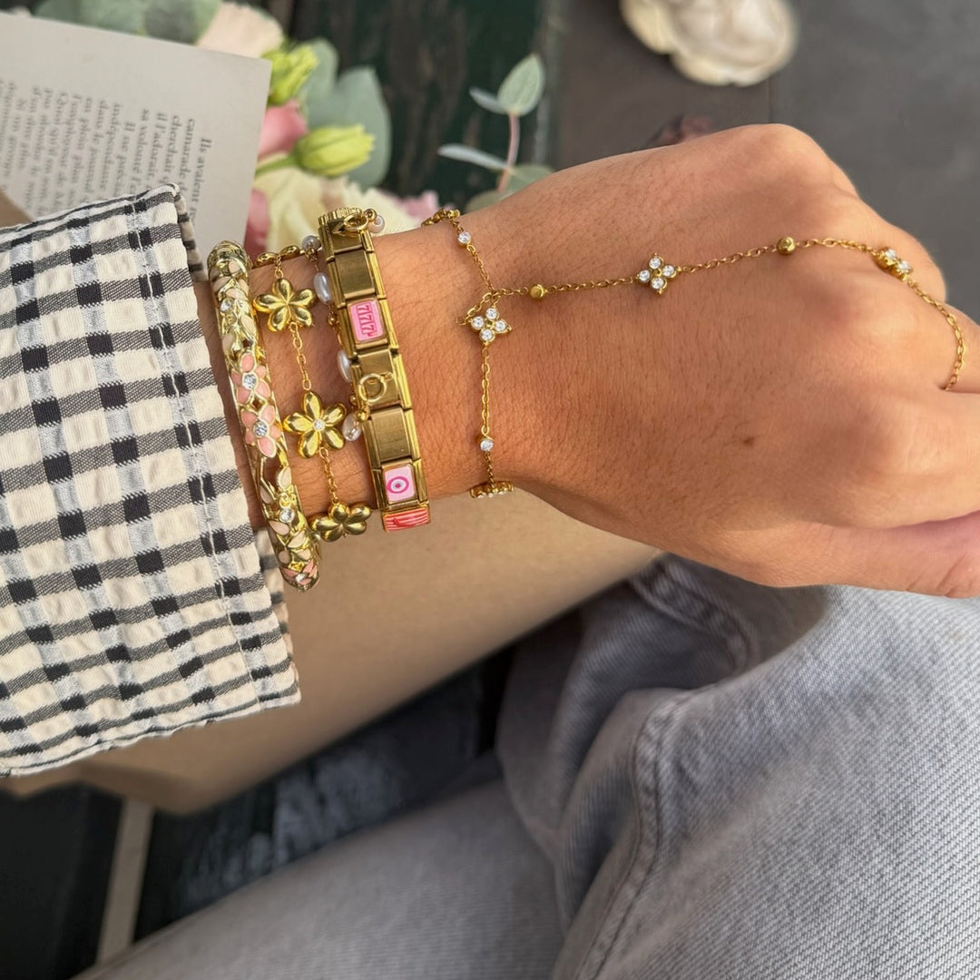 Bracelet Flora porté au poignet en accumulation avec d'autres bracelets dorés